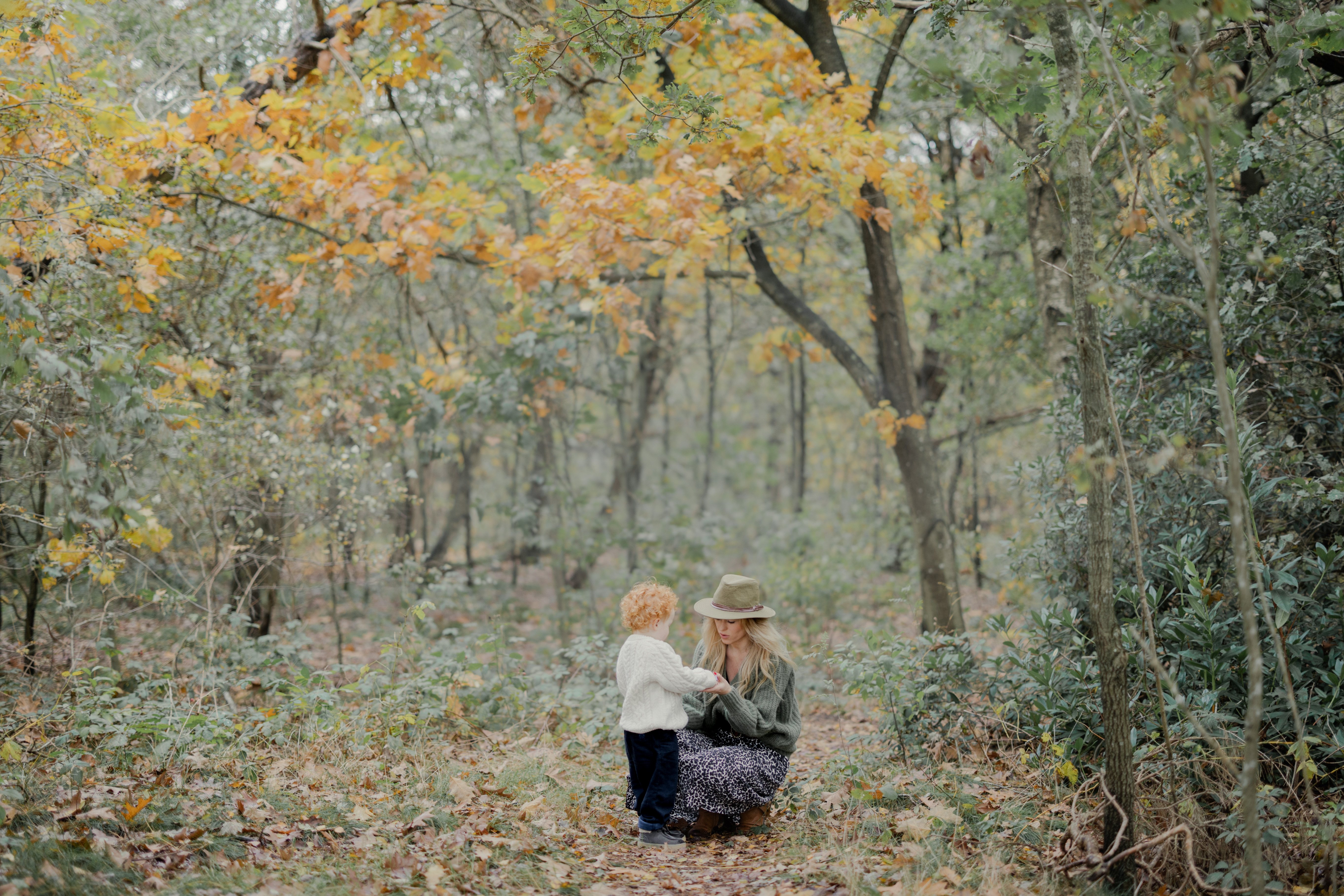 Moeder en kind hand in hand in herfstbos